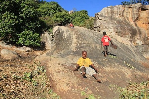 Children sliding down a boulder